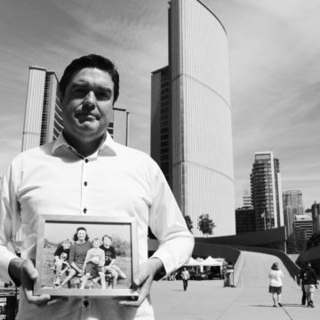 Photo of David Stark holding a picture of his family in a frame outside of Toronto City Hall