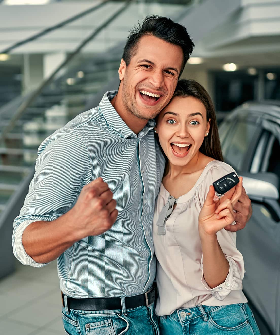 Young couple with keys at dealership
