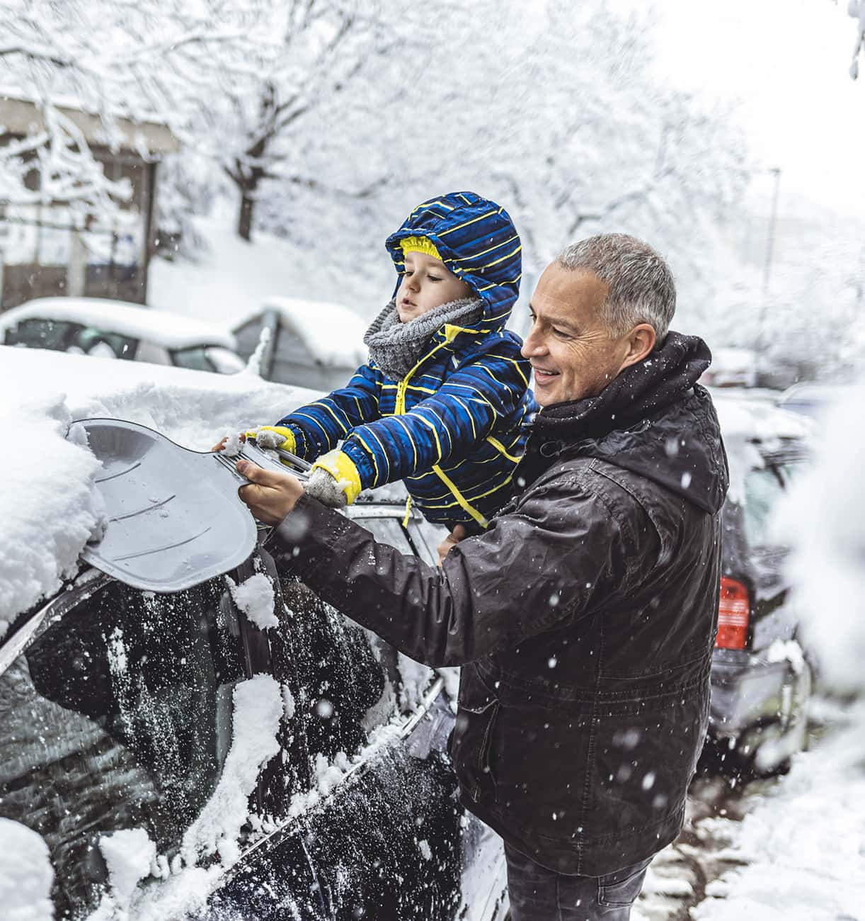 Father and son clearing snow from the car